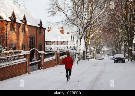 Un runner su una coperta di neve strada in Woodthorpe, Nottingham, Inghilterra, Regno Unito Foto Stock