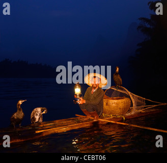 Cormorano pescatore con lampada su zattera di bambù all alba Li o Fiume Lijiang Xingpingzhen Yangshuo, Guilin, Guangxi Cina Foto Stock