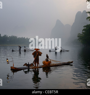 I pescatori di cormorani in bambù zattere presso l'alba sul fiume li carsico con picchi di montagna vicino xingping cina Foto Stock