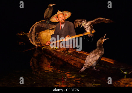 Cormorano fisherman holding bird su un palo su una zattera di bamboo sul Li o Fiume Lijiang di notte Xingpingzhen Yangshuo, Guilin, Guangxi Cina Foto Stock