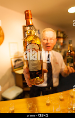 Un barman visualizza una bottiglia di Arran Scotch whisky al Isle of Arran Distillery a Lochranza sull'isola di Arran. Foto Stock