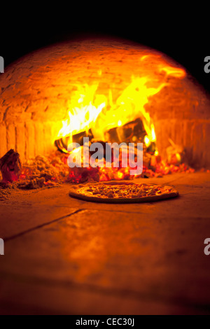 La cottura della pizza all'aperto in un forno a legna Foto Stock