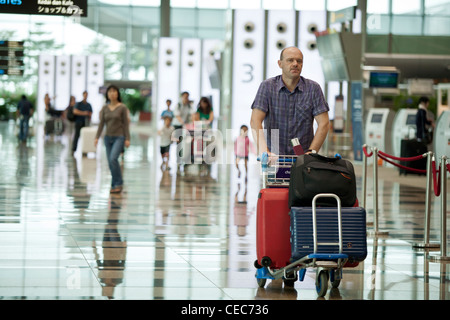 Passeggeri a piedi attraverso la zona partenze del Terminal 3 dell'Aeroporto Changi di Singapore Foto Stock