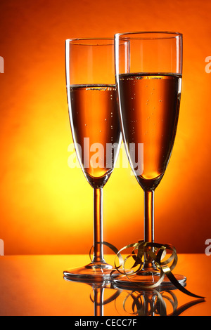 Due bicchieri di champagne e streamer oro su sfondo giallo Foto Stock