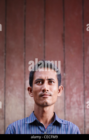 Ritratto di metà adulto uomo asiatico cercando fino contro la parete marrone. Spazio di copia Foto Stock