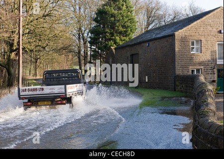 Allagamento - veicolo (carrello) guidare & spruzzi attraverso le profonde acqua di inondazione su allagata strada rurale dopo la pioggia torrenziale - North Yorkshire, Inghilterra, Regno Unito. Foto Stock