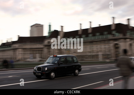 Un taxi che viaggiano sul Westminster Bridge e superato il County Hall di Londra Foto Stock