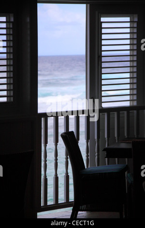 Una sedia accanto a una finestra che guarda sull'Oceano Atlantico sul lato est di Barbados, West Indies Foto Stock