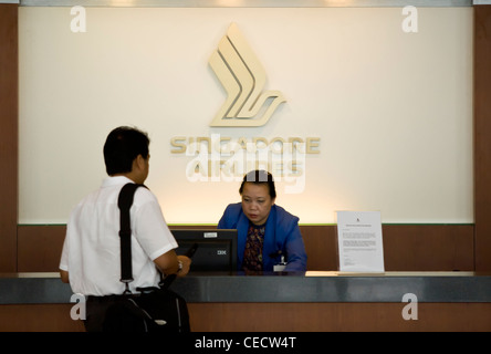 Un dipendente aiuta un passeggero al Singapore Airlines Ltd. informazioni contatore nel terminal 3 dell'Aeroporto Changi di Singapore Foto Stock