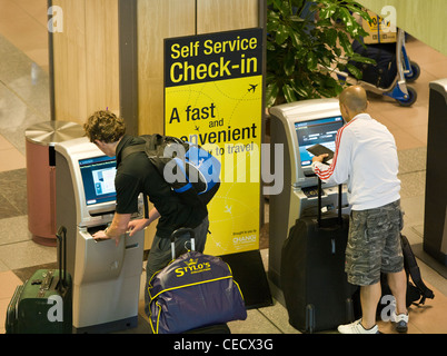 I passeggeri effettuano il check-in presso il self service chioschi presso l'Aeroporto Changi di Singapore Foto Stock