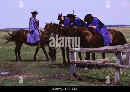 Csikos allevatori di cavalli in abbigliamento tradizionale siedono sulla razza Nonius nella vasta pianura ungherese chiamata Puszta del Parco Nazionale di Hortobagy vicino a Debrecen nell'Ungheria orientale Foto Stock