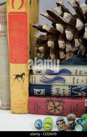 Vintage per bambini libri a copertina rigida ed un vasetto di marmi su una tavola di legno da scaffale Foto Stock