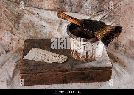 Vecchia spazzola di pittura con contenitore carta vecchia e decoratori grembiule come sfondo Foto Stock