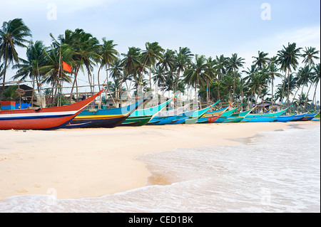 Le tradizionali dello Sri Lanka barche di pescatori sulla spiaggia dell'oceano Foto Stock