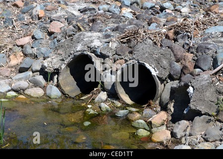 Le tubazioni di scarico contemplate nelle rocce e cemento Foto Stock