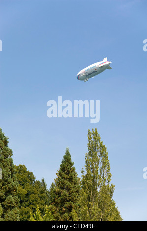 Vista verticale di un grande dirigibile, Zeppelin, flottante su alberi in un cielo blu. Foto Stock