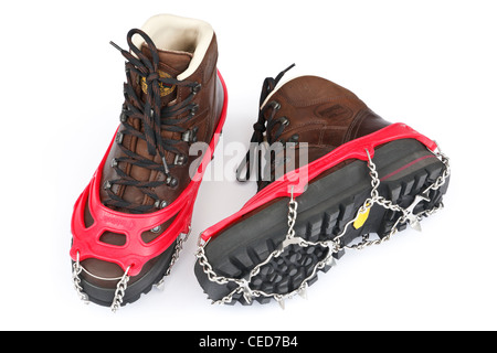 Una coppia di tradizionali in pelle marrone scarponi con Kahtoola microspikes per utilizzo su ghiaccio e neve isolato su uno sfondo bianco. Regno Unito Foto Stock