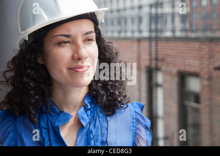 Sorridente imprenditrice ispanica indossando hard-hat Foto Stock