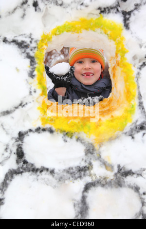 Ragazzo con palla di neve nella fortezza di neve Foto Stock