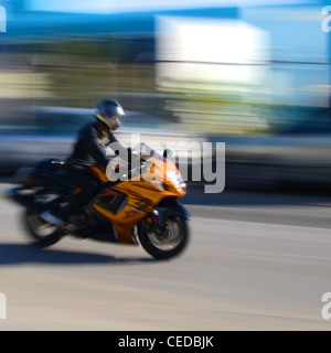 Un arancione è in moto accelerando sulla strada. Foto di panning. Foto Stock