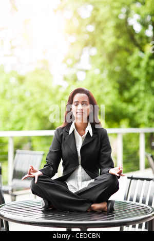 Indian imprenditrice a praticare yoga sul piano portapaziente Foto Stock