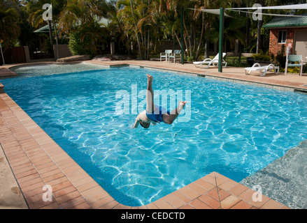 Ragazzo adolescente salto in una piscina in estate Foto Stock