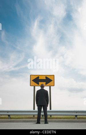 African American businessman guardando il conflitto di cartello stradale Foto Stock