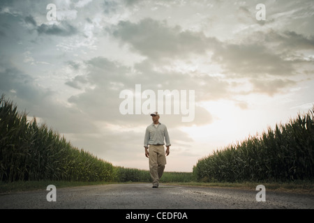 African American Farmer camminando sulla strada attraverso le colture Foto Stock