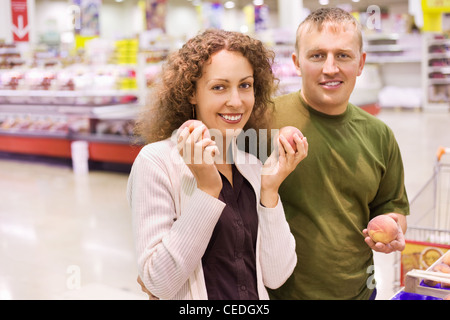 Sorridente giovane uomo e donna acquista pesche al supermercato Foto Stock