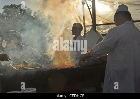 Il Nord Africa, Marocco, Marrakech, Djemaa el-Fna (piazza principale), bancarelle con nebbia dalla cottura di carne - in presenza di intensa luce solare Foto Stock