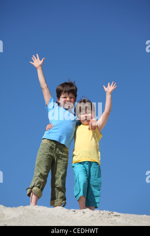 Due ragazzi di stare sulla sabbia e alzato le mani nel messaggio di saluto Foto Stock