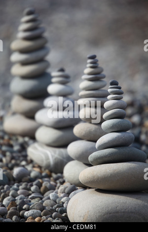 Quattro pile di pietra sulla spiaggia di ciottoli su sfondo di pietra Foto Stock