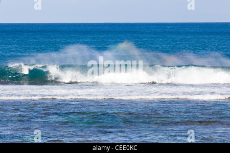 Onde che si infrangono sulla barriera corallina della costa di Kauai e formare i colori dell'arcobaleno in spray Foto Stock