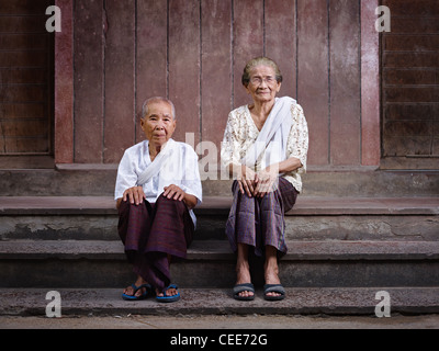 Ritratto di due vecchie donne asiatiche seduti sui passi al di fuori della loro casa e guardando la fotocamera Foto Stock