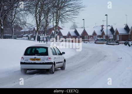 Un bianco auto guidare in condizioni di pericolo nella neve in una zona residenziale a Nottingham REGNO UNITO Inghilterra Foto Stock