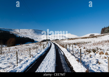 Una coperta di neve la via conduce verso montagne coperte di neve Foto Stock