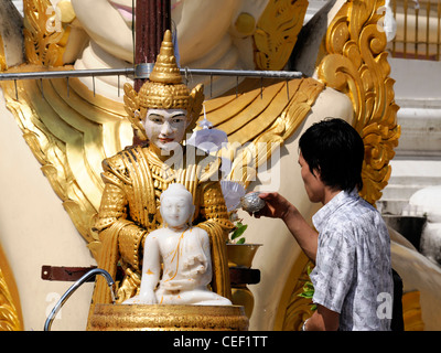 Devoto pellegrino pour versando acqua facendo offrendo alla statua del Buddha post planetari Shwedagon pagoda myanmar Foto Stock