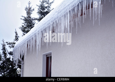 Ghiaccioli appesi da una coperta di neve sul tetto. Oberbergisches Land, Renania settentrionale-Vestfalia (Germania). Foto Stock