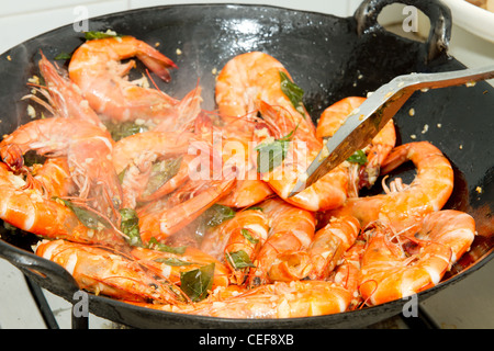 Friggere i gamberi con foglie di curry e aglio in un wok Foto Stock