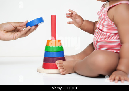 Madre la mano dando baby un pezzo di un edificio in legno toy Foto Stock