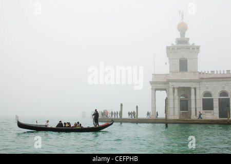 Una gondola attraversa il Bacino di San Marco nella fitta nebbia di fronte alla Punta della Dogana. Venezia, Italia. Foto Stock