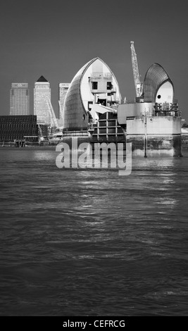 Thames Barrier in bianco e nero ritratto di uno dei cancelli con Canary Wharf in background (ctigroup & HSBC) Foto Stock