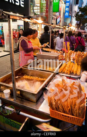 Strade cibo bancarelle che vendono vari cibi e spuntini in serata nel famoso quartiere dello shopping di a Myeongdong a Seul Foto Stock