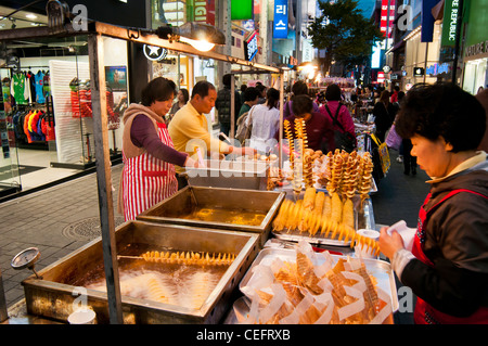 Strade cibo bancarelle che vendono vari cibi e spuntini in serata nel famoso quartiere dello shopping di a Myeongdong a Seul Foto Stock