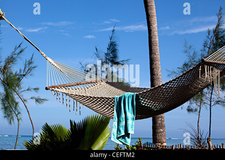 Amaca in Palm Beach Inn' di onde che si infrangono sulla barriera corallina in distanza, Bwejuu village isola di Zanzibar, Tanzania Foto Stock