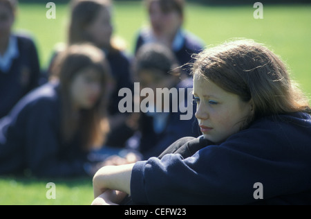 Infelice teenage schoolgirl essendo cajoled dai suoi pari Foto Stock