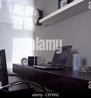 Computer portatile sulla pelle nera scrivania con matite in un barattolo di vetro in modern home office Foto Stock