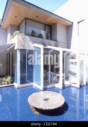 Circolare funzione acqua in piscina poco profonda con piastrelle blu nella parte anteriore della casa moderna con estensione in vetro Foto Stock