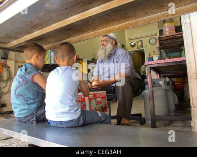 Palestina,West Bank,Bhetlehem,area di Betlemme. Il vecchio uomo della Palestina con bambini dentro il suo negozio tradizionale. Foto Stock