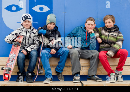 Un gruppo di adolescenti amici e skateboarders seduto su una panchina nella città di Sortland, Norvegia Foto Stock